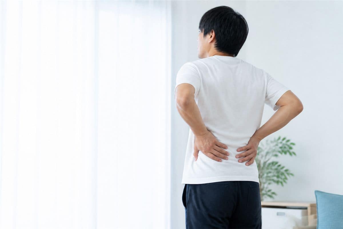 腰に手を当てて腰痛に悩む男性